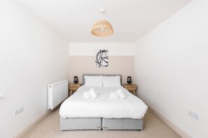 Ein Schlafzimmer mit einem Bett, zwei Nachttischen, einer Wandleuchte und einer Heizung.