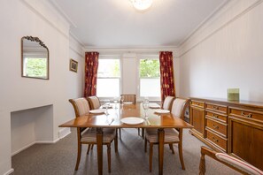 Ein Esszimmer mit einem Holztisch, sechs Stühlen und einem Holzschrank.