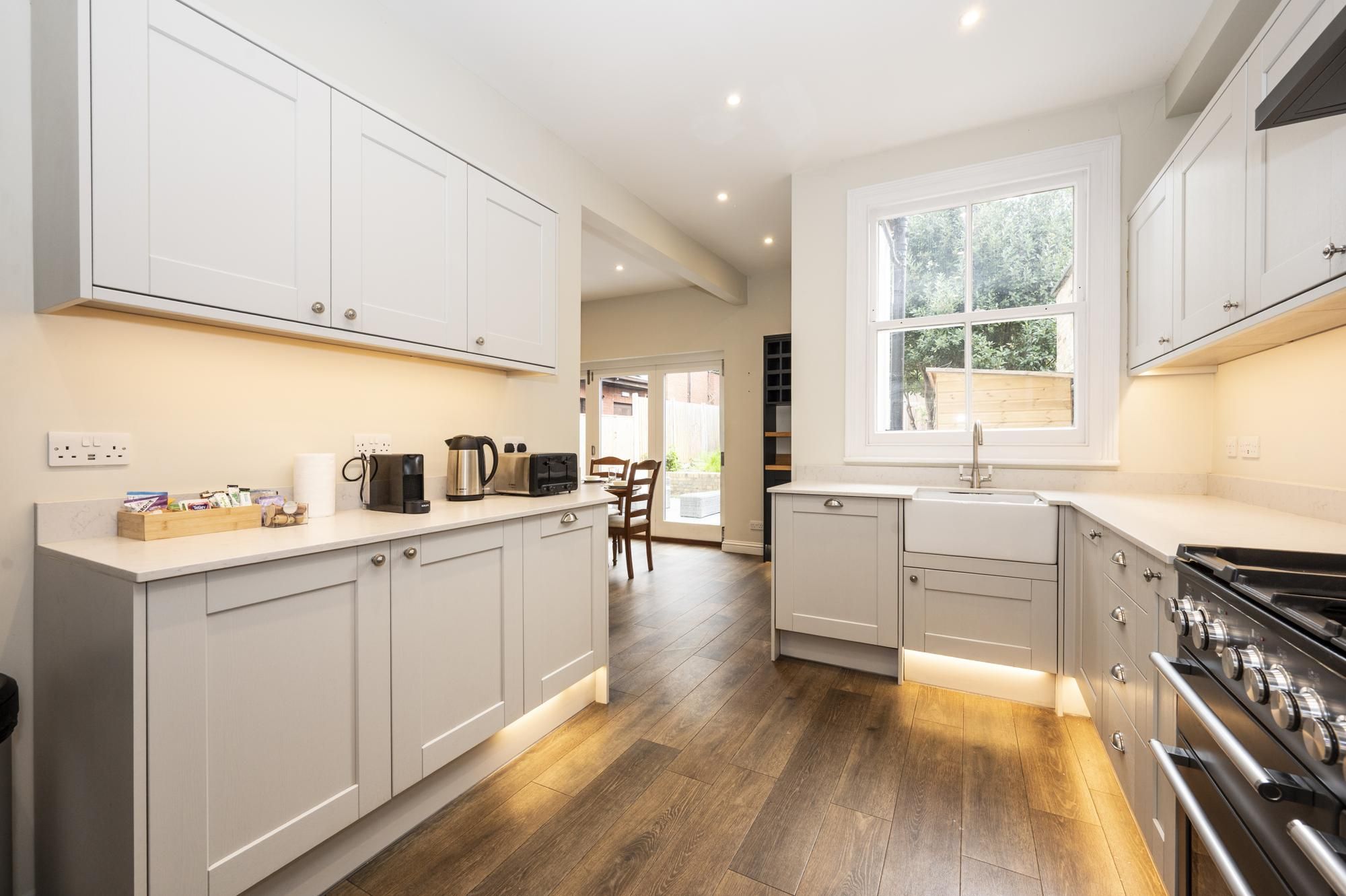A modern kitchen with white cabinets, a large window, and a built-in stove.