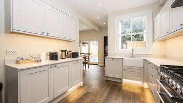 A modern kitchen with white cabinets, a large window, and a built-in stove.