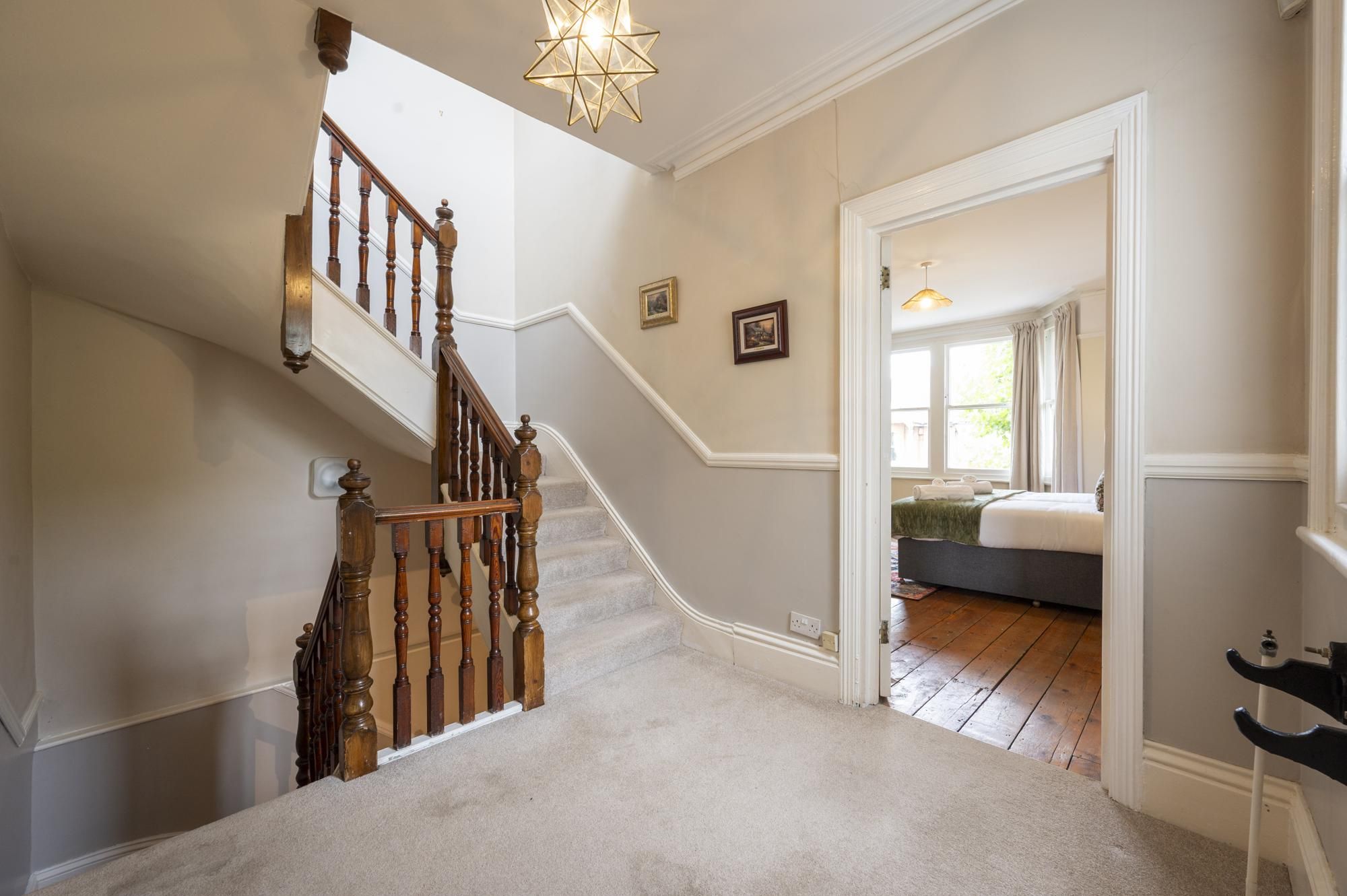 A staircase with wooden balusters leading to a bedroom with a bed and a window.