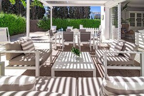 An outdoor patio area with white furniture, including sofas and chairs, arranged around a central table with a plant. - LVB92 - Beautiful 4-Bed Townhouse in Guadalvilla (San Pedro)