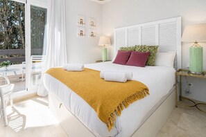 Quarto de hotel com cama, duas mesas de cabeceira, janela com cortinas e vista para árvores.