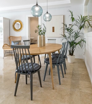 A dining area with a round wooden table, grey upholstered chairs, and two hanging pendant lights. - LVB92 - Beautiful 4-Bed Townhouse in Guadalvilla (San Pedro)