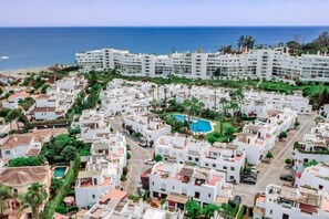 A coastal residential area with white buildings, a central swimming pool, and a beach in the background. - LVB - Casa Linda vista by roomservices (San Pedro Alcántara)