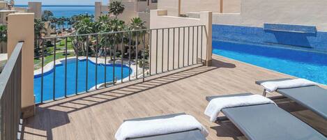 A rooftop pool area with lounge chairs and a view of the ocean.