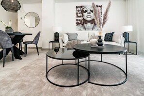 A modern living room with a round coffee table, a sofa, and a dining area with chairs and a table. - INf27E- Holiday home Estepona by roomservices (Estepona)