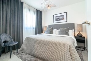 A hotel room with a bed, a chair, a bedside table with a lamp, and a cityscape picture on the wall. - INf27E- Holiday home Estepona by roomservices (Estepona)