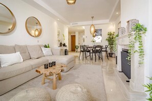 Un salon moderne comprenant un canapé, une table basse, une table à manger, des chaises et une cheminée.