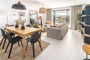 Uma sala de estar moderna com área de jantar, sofá e televisão.