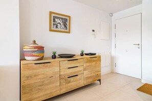 Um armário de madeira com gavetas, um quadro emoldurado na parede e uma porta branca.