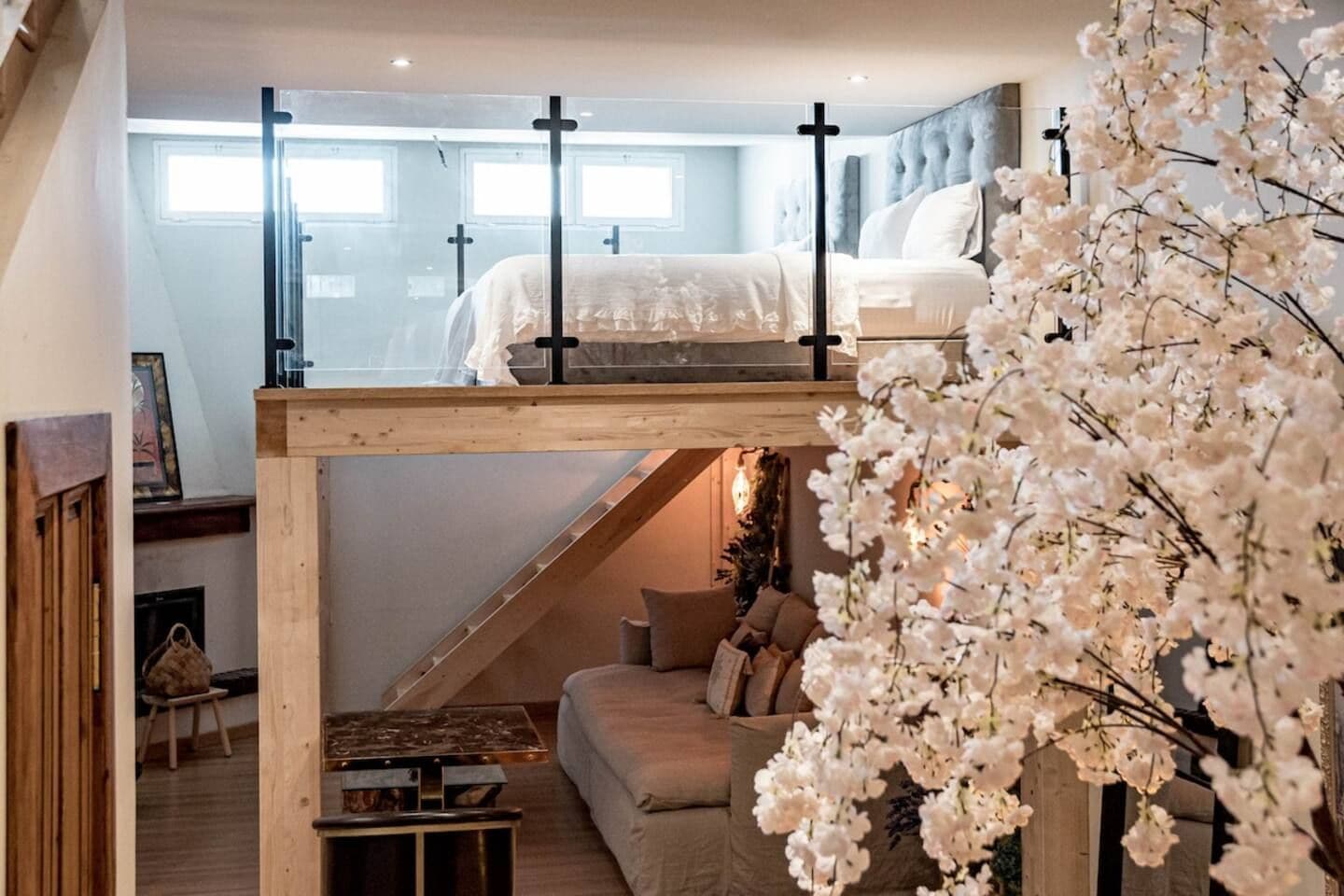 Dormitorio tipo loft con una cama litera, una escalera y una zona de estar con sofá y una mesita.