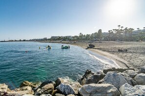 A beach with rocky shoreline, clear water, and a few boats. - Beachside Apartment with Pool, Puerto Banus- PR20 (Marbella)