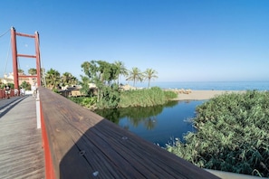A wooden boardwalk leading to a beach with palm trees and a clear sky. - Beachside Apartment with Pool, Puerto Banus- PR20 (Marbella)