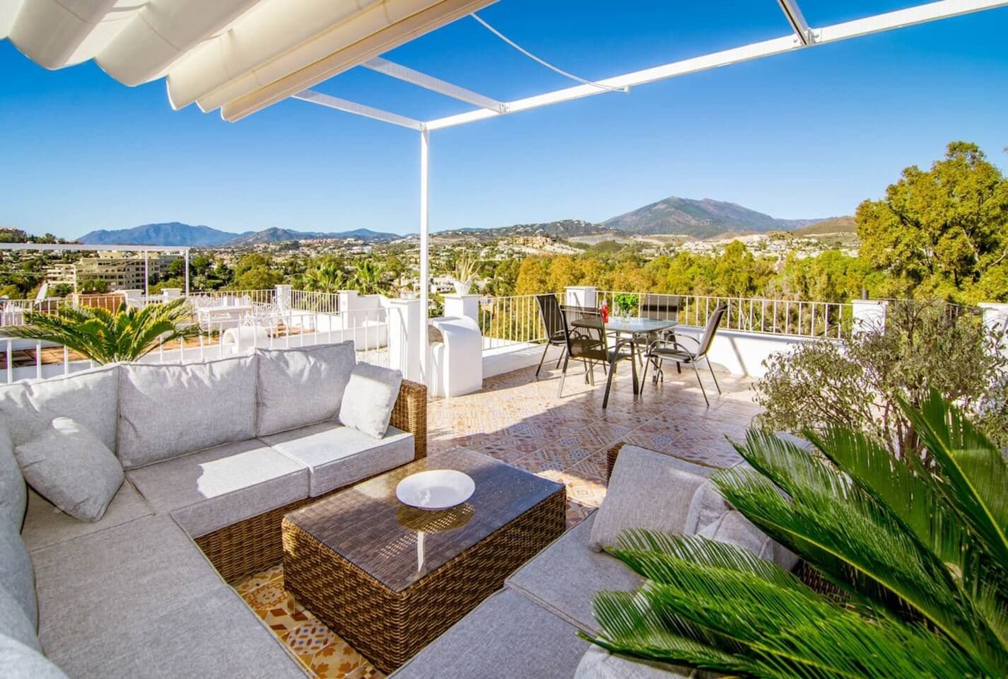 Una terraza en la azotea con un sofá blanco, una mesa de comedor y sillas.
