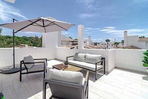 A rooftop terrace with a white sofa, a coffee table, and a large umbrella. - LNm530 - Great location with private roof terrace (Marbella)