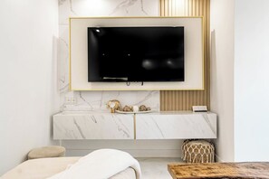 Ein modernes Wohnzimmer mit Marmorwand, einem Wand-Fernseher, einem Holzschrank und einer gemütlichen Sitzecke.