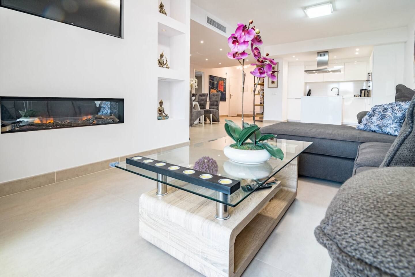 Un salon moderne avec une table basse en verre, un canapé et une cheminée.