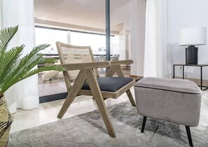 A modern living room with a rattan chair, a grey ottoman, and a floor lamp. - DJC- Modern 2 bedroom apartment close to beach (Casares)