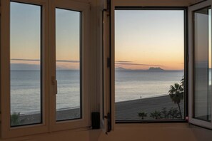 Une chambre avec vue sur la mer, offrant un panorama magnifique au coucher du soleil, et dotée d’un balcon avec une porte vitrée.