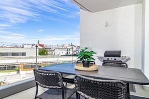 A balcony with a table, two chairs, a grill, and a potted plant. - INf31J - Stunning holiday home next to beach (Estepona)