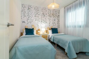 A hotel room with two beds, a nightstand, a lamp, and a window with sheer curtains. - INf31J - Stunning holiday home next to beach (Estepona)