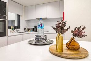 Een moderne keuken met een waterdispenser, een decoratief bord en twee vazen op het aanrecht.
