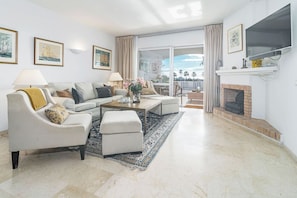 A modern living room with a sofa set, coffee table, and a fireplace. - MA - Elegant Apartment with Sea views (Marbella)
