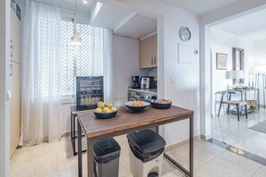 Eine moderne Küche mit einem Holztisch, zwei Mülleimern und einem Kühlschrank.