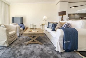 Ein modernes Wohnzimmer mit einer Couch, Sesseln, einem Couchtisch und einem Fernseher.
