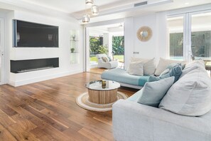 A modern living room with a flat-screen TV, a round coffee table, and a grey sofa with multiple cushions. - Villa Nottingham Stunning private villa (Marbella)