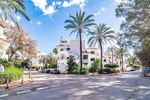 A street lined with palm trees and white buildings, cars parked along the side, and a clear blue sky. - GBH - Casa Golden beach by Roomservices (Marbella)