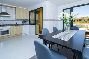 A modern kitchen with a stove, oven, and cabinets, leading to a dining area with a table and chairs. - 3-Bed Penthouse Close to the Beach - LA (Marbella)