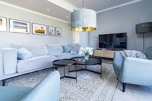 A modern living room with a sectional sofa, a round coffee table, a TV, and a patterned rug. - 3-Bed Penthouse Close to the Beach - LA (Marbella)