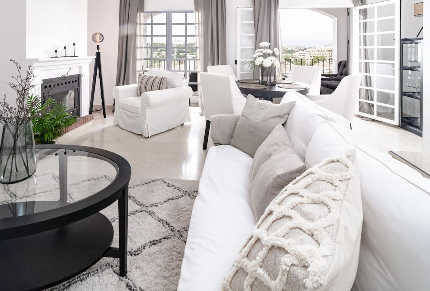Una sala de estar moderna con un sofá blanco, una mesa redonda de centro y una chimenea.
