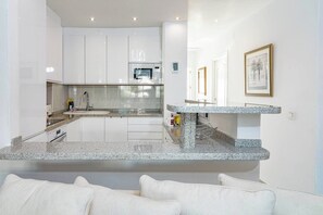 A modern kitchen with white cabinetry, granite countertops, and a built-in microwave. - RG325 - Great 2 Bed Apt, close to Puerto Banus (Marbella)