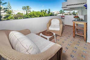 Ein Balkon mit einer Rattan-Couch, einem kleinen Tisch und einem Stuhl.