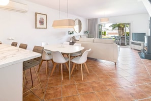 Ein modernes Wohnzimmer mit einer Couch, einem Esstisch und Stühlen. Es gibt einen Fernseher und einen Kamin.