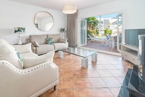 A modern living room with a sofa, a glass coffee table, and a television. - Andalucian Townhouse, Pool, Near Estepona (Estepona)
