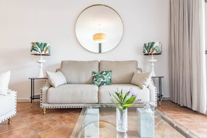 Ein Wohnzimmer mit einer Couch, zwei Beistelltischen, einem Couchtisch und einem großen Spiegel an der Wand.