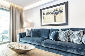 A modern living room with a dark blue sofa, patterned cushions, a wooden coffee table, and a framed artwork on the wall. - AE - Wonderful apartment in San Pedro centro (San Pedro de Alcantara)