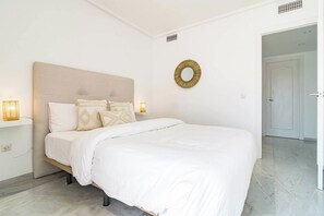 A bedroom with a bed, bedside lamps, a wall-mounted mirror, and a door leading to another room. - TEnis - Bright Bel-Air flat 2 beds, 3 terraces (Bel-Air)