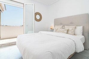 Un dormitorio con una cama grande, un espejo redondo y una mesita de noche con una lámpara.