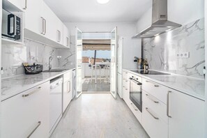 A modern kitchen with white cabinetry, a built-in oven, and a view through an open door to an outdoor patio. - TEnis - Bright Bel-Air flat 2 beds, 3 terraces (Bel-Air)