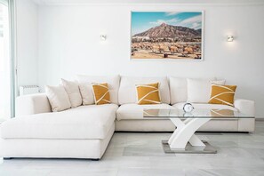 A modern living room with a sectional sofa, a glass coffee table, and a framed landscape painting on the wall. - TEnis - Bright Bel-Air flat 2 beds, 3 terraces (Bel-Air)