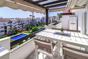 A balcony with a table and chairs, overlooking a swimming pool and a garden with palm trees. - TEnis - Bright Bel-Air flat 2 beds, 3 terraces (Bel-Air)