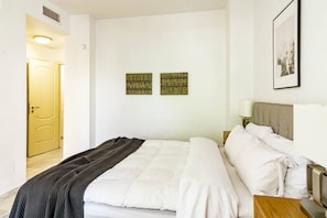 A hotel room with a bed, bedside tables, a lamp, and two wall-mounted artworks. - FA - Well-equipped apartment in a great location (Marbella)