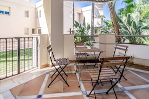 A terrace with a table and chairs, surrounded by a metal fence and plants. - FA - Well-equipped apartment in a great location (Marbella)