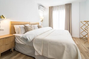 A bedroom with a bed, bedside table, lamp, and a window with curtains. - Bright 2BR, Sea Views, Near Beach, Estepona EAC3F (Estepona)