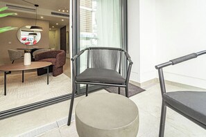 A modern interior with a round table, two chairs, a vase with red flowers, and a large mirror. - LE2C Luxury New build apartment near the beach (Estepona)